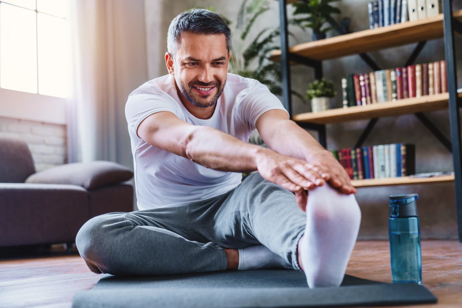Foco flexível A imagem tem um homem se alongando em casa.